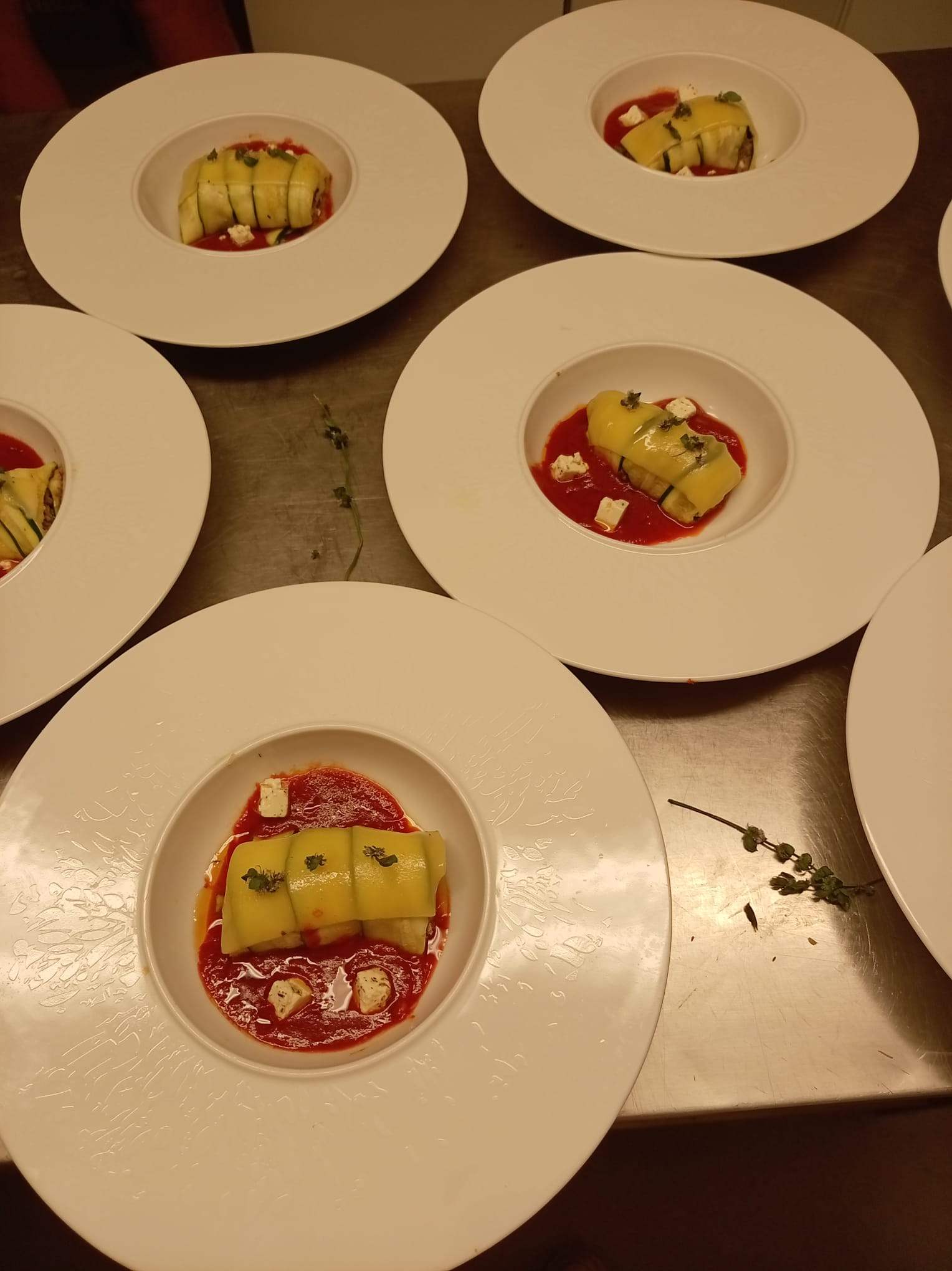 Assiettes dressées en série sur le passe de la cuisine, prêtes à partir en salle.