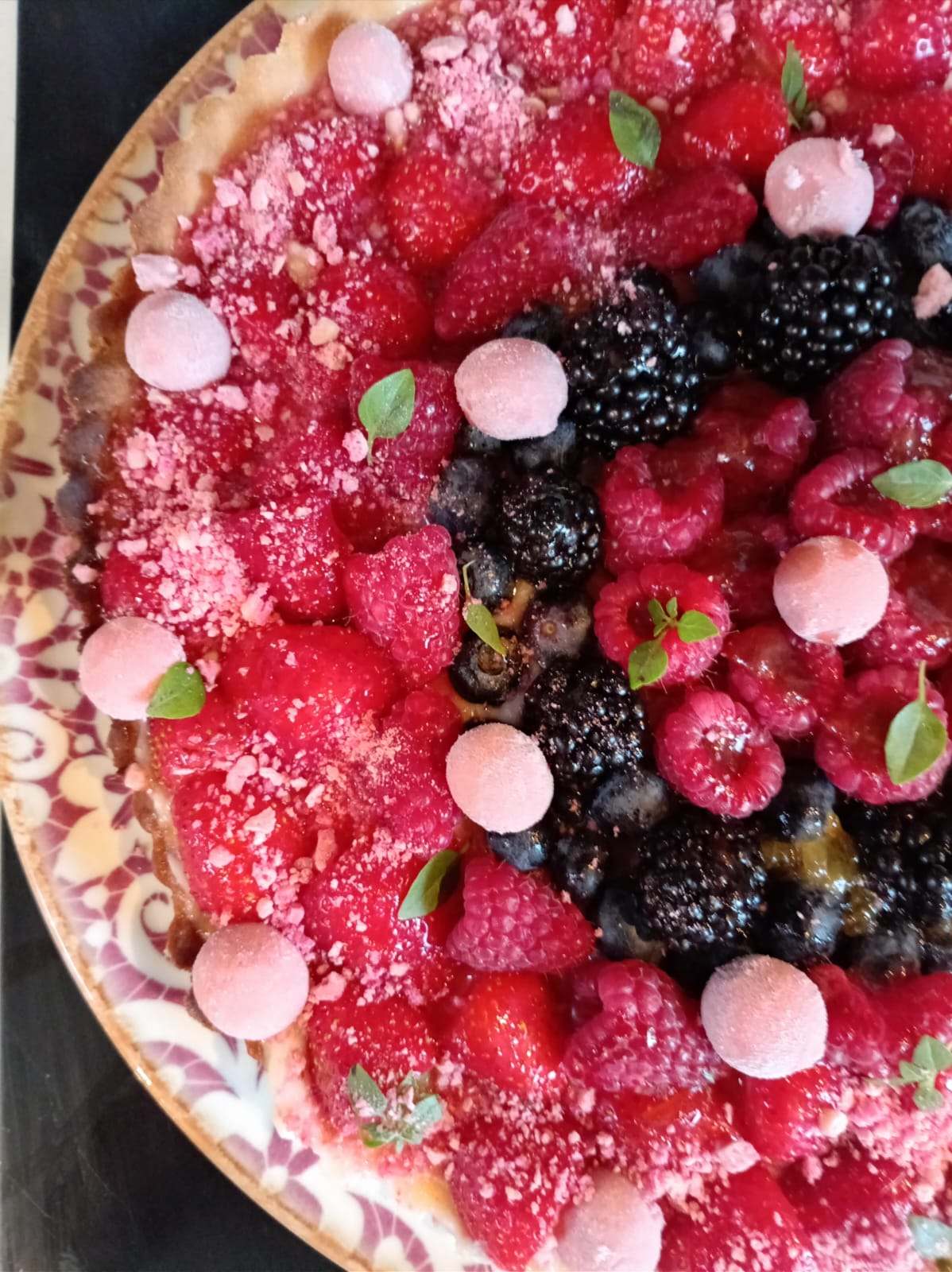 Grande tarte aux fruits rouges : framboises, mûres, myrtilles et petites meringues roses.